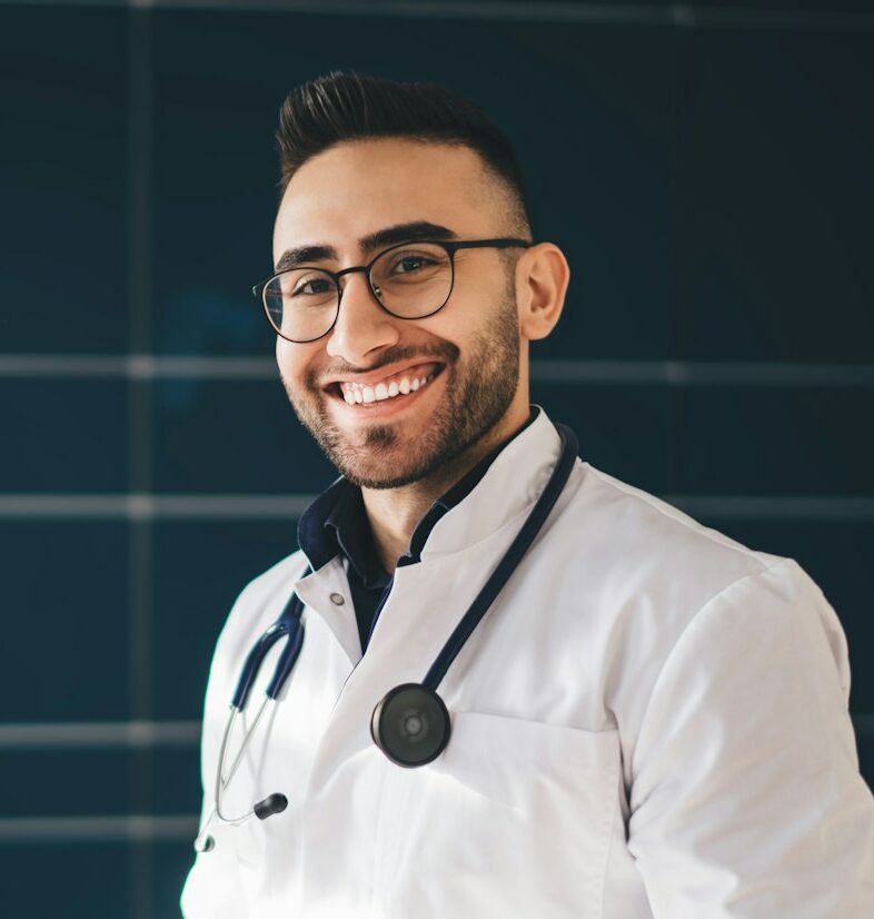 Cheerful male doctor in medical uniform working in hospital