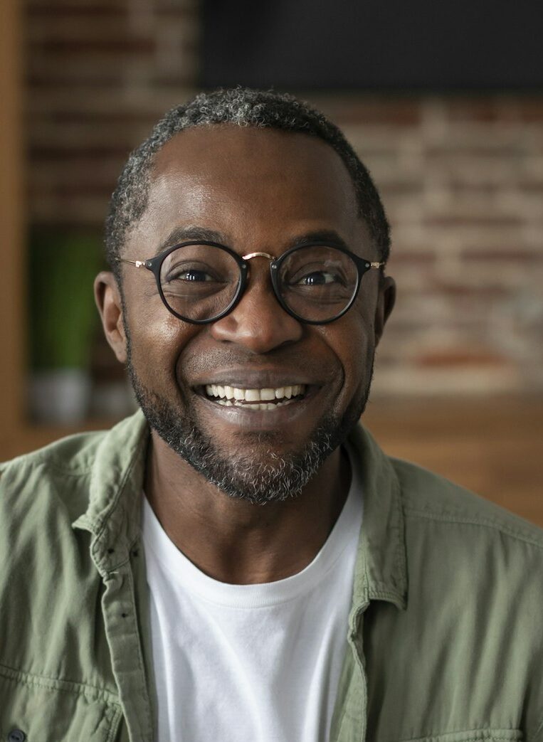 Headshot of smiling middle aged african american male waving hand at camera, greets, says hi, has