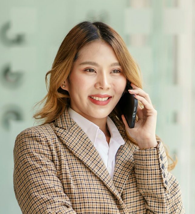 Pretty young Asian business woman standing talking on the phone in the office.